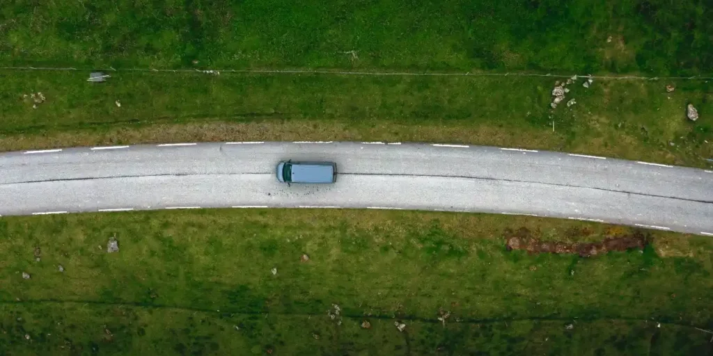 Camper van driving along winding coastal road, Faroe Islands