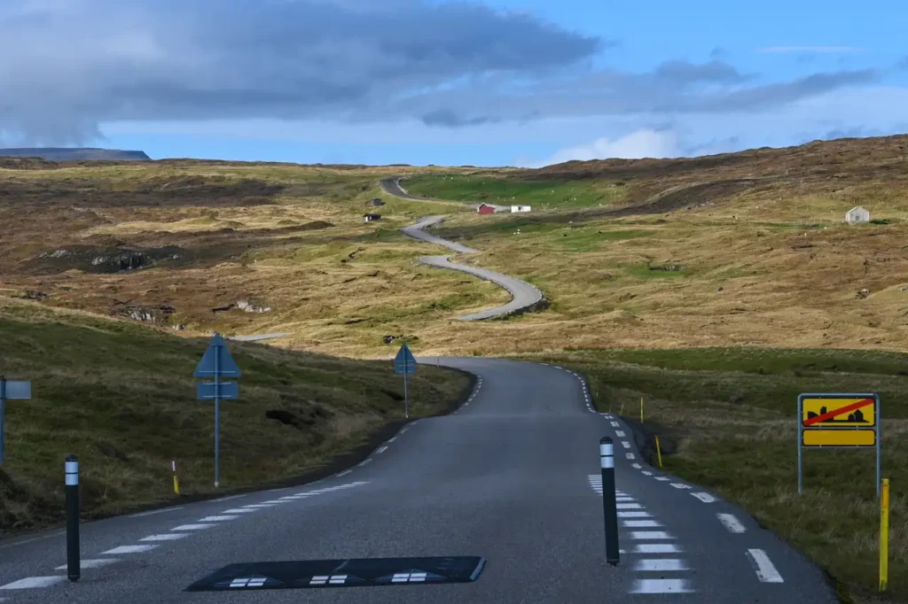 Winding rural road through grassy hills near Æðuvík in the Faroe Islands