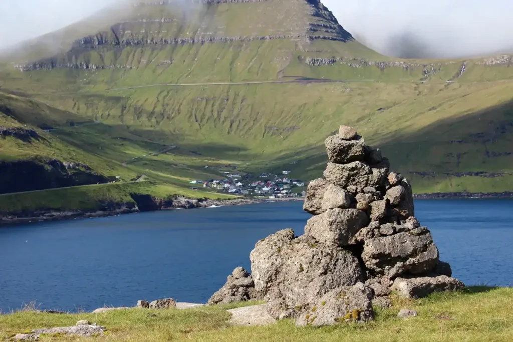 Stacked stone cairn overlooking a fjord and village in the Faroe Islands