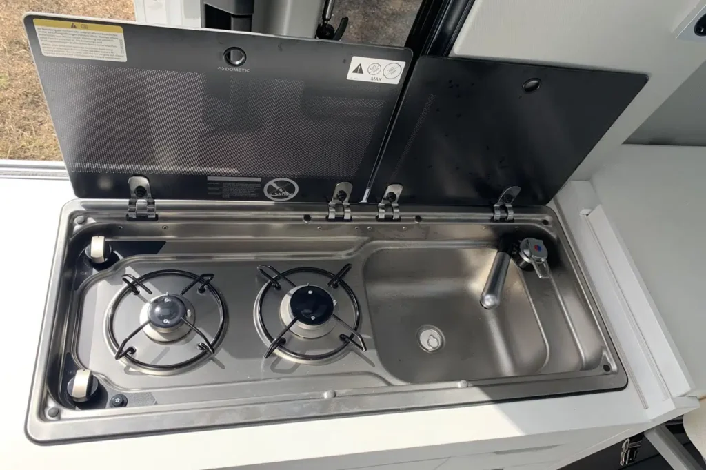 Campervan kitchenette with two-burner gas stove and integrated stainless steel sink