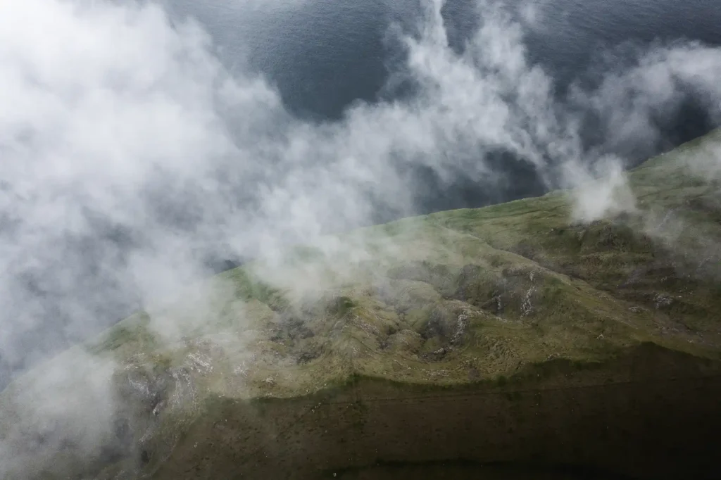 Misty coastal cliffs covered in fog above the ocean in the Faroe Islands