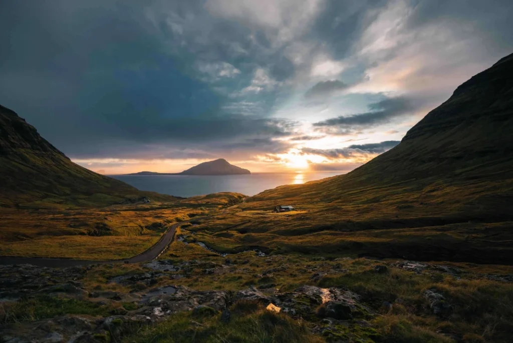 Sunset view over a valley and ocean in the Faroe Islands with mountains on both sides