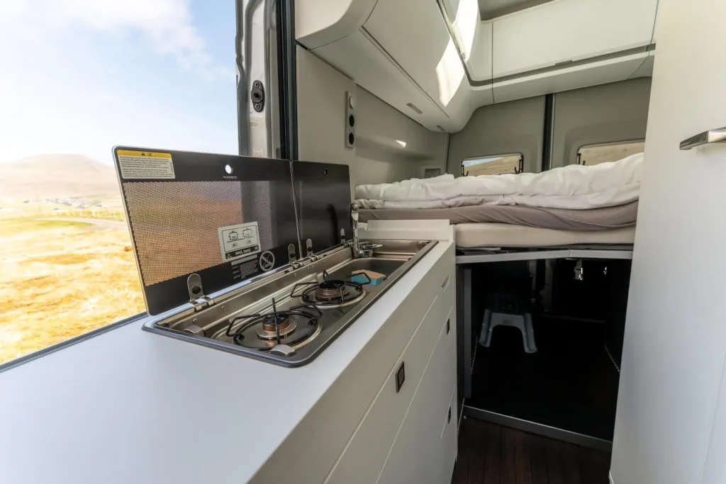 Campervan interior with a compact kitchen and raised bed