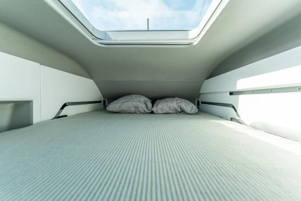 Campervan upper sleeping area with skylight and double bed inside a VW van