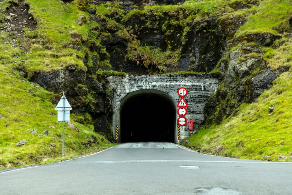 tunnel-Faroe-Islands Old single-lane mountain tunnel entrance surrounded by green cliffs in the Faroe Islands