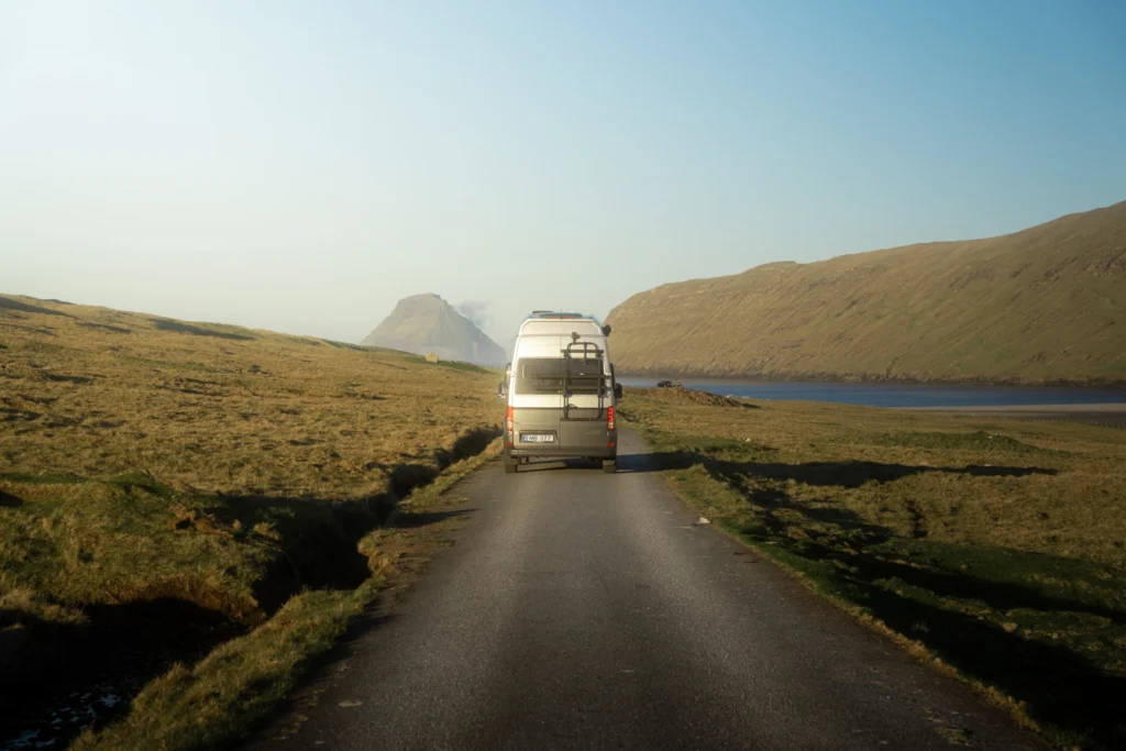 Campervan driving through remote landscape in the Faroe Islands